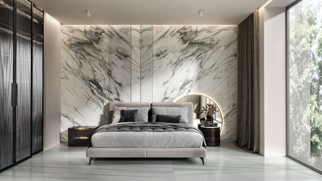 Luxury bedroom featuring a dramatic bookmatched Italian marble accent wall behind a modern upholstered bed, complemented by soft lighting and floor-to-ceiling windows.